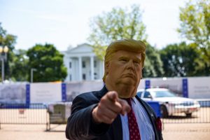 man wearing Donald Trump mask standing in front of White House