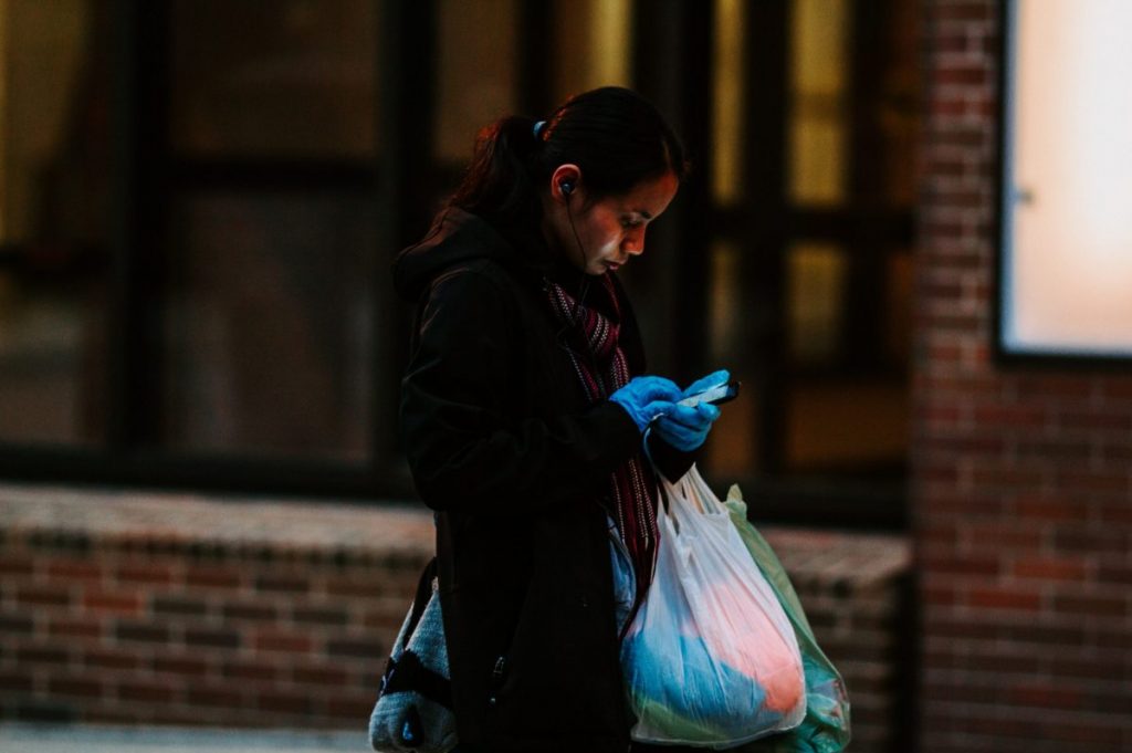 woman in black jacket holding pink plastic bag