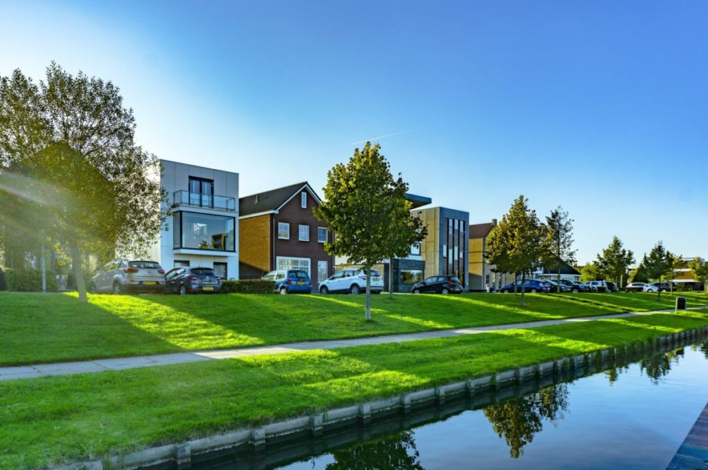 white and brown house near green grass field and body of water during daytime