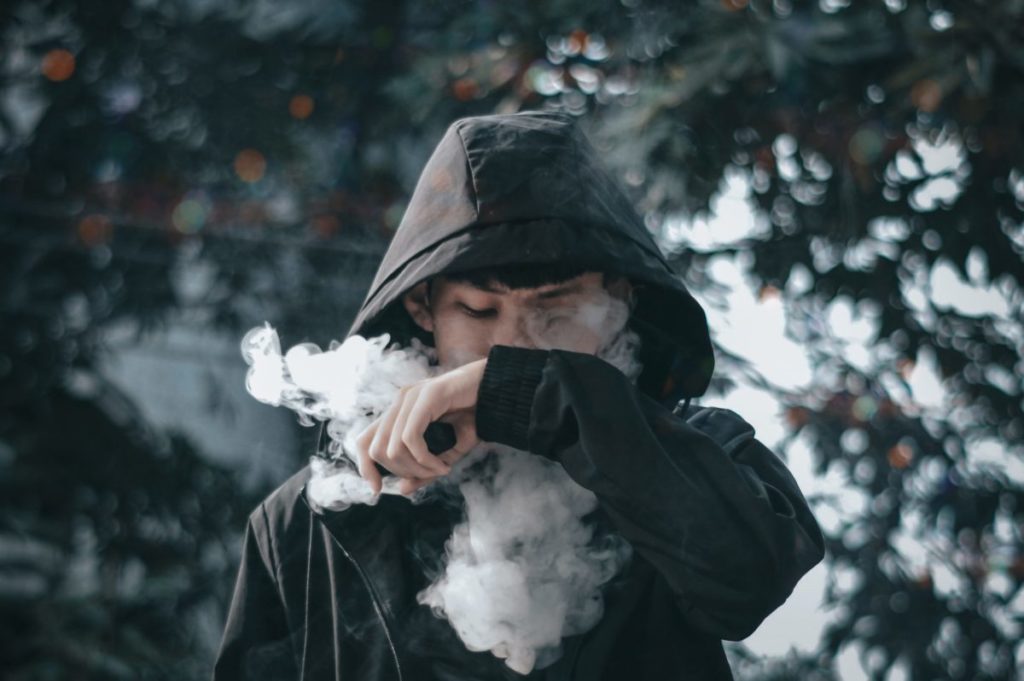 man in black hoodie holding white flower