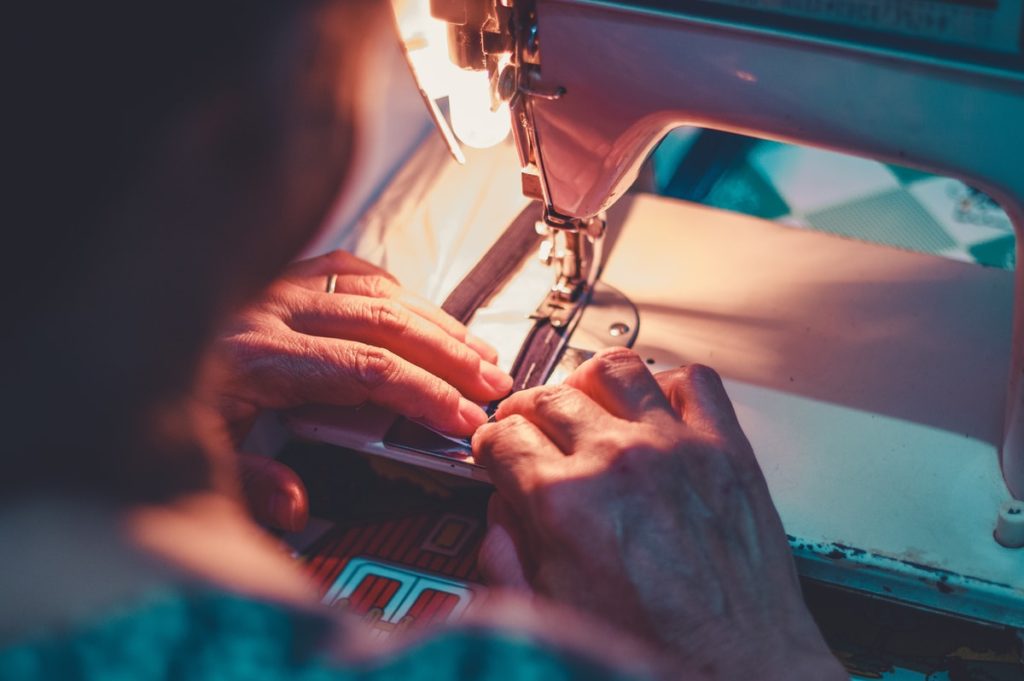 person playing sewing machine with white sewing machine