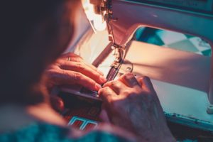 person playing sewing machine with white sewing machine