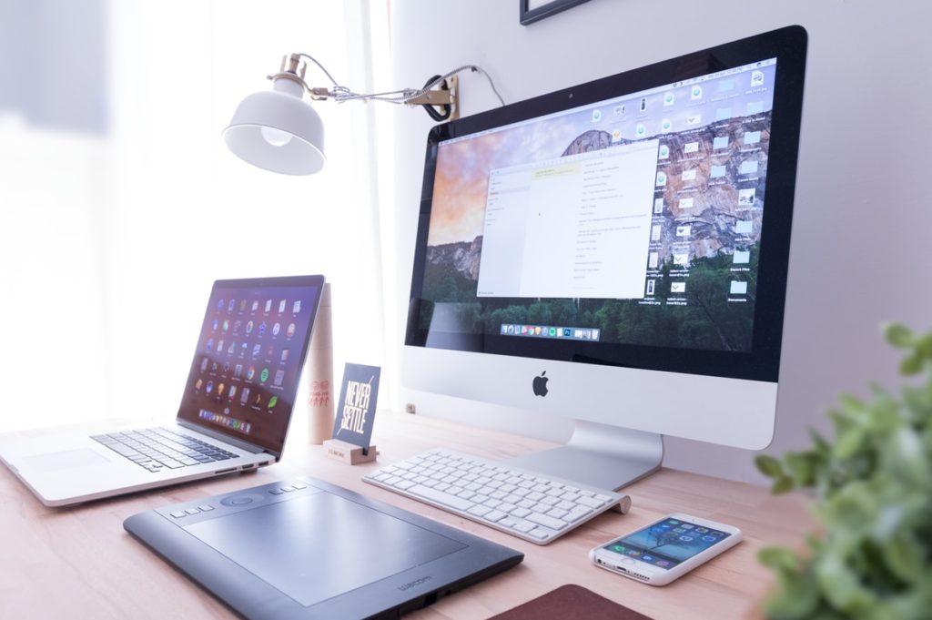 silver iMac near iPhone on brown wooden table