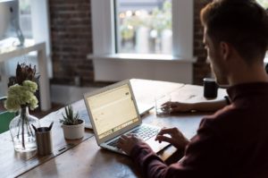 man operating laptop on top of table