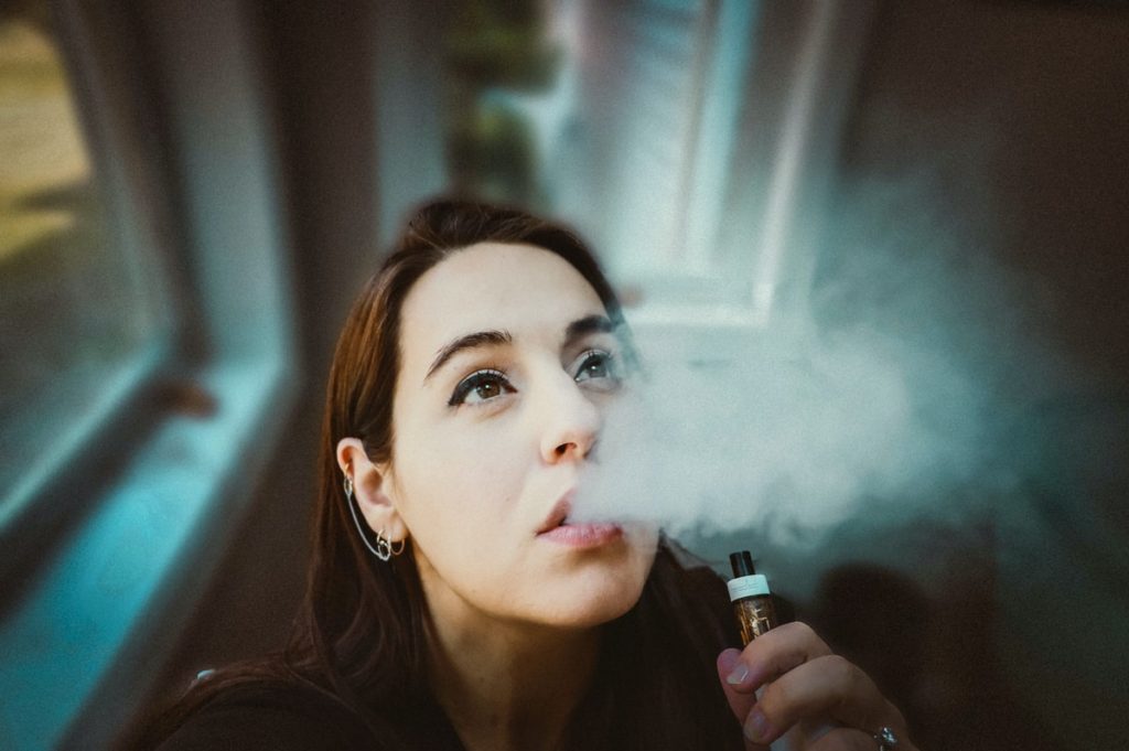 woman holding black and gold tube type vape